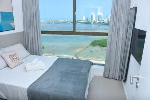 a bedroom with a bed with a view of the ocean at Vista mar - Flat Parque do Cais 1211 in Recife +24 photos