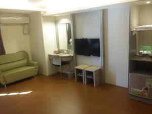 uma sala de estar com um sofá verde e uma televisão em KD Hotel em Douliu