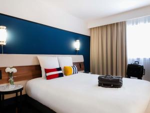 een hotelkamer met een groot bed met een tas erop bij Mercure Caen Centre Port De Plaisance in Caen