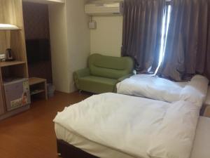 a hotel room with a bed and a green chair at KD Hotel in Douliu