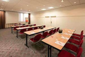 a conference room with long tables and red chairs at ibis Nürnberg City am Plärrer in Nürnberg