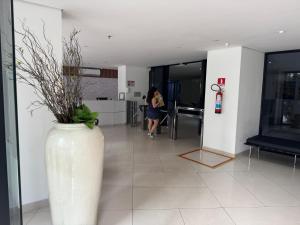 Apto Landscape beira mar في فورتاليزا: امرأة في غرفة بها مزهرية بيضاء كبيرة +37 صورة