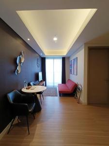 a living room with a table and a red couch at gold coast pik BEACH ROOM 1br netflix wifi sofa bed in Jakarta +6 photos