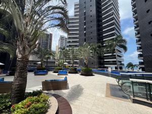 Apto Landscape beira mar في فورتاليزا: منتجع فيه مسبح والنخيل والمباني