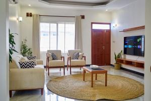 a living room with chairs and a tv and a table at Elegant Dar Suburb Hideaway2 in Dar es Salaam