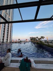 una mujer sentada en una piscina en una ciudad en Pollux habibie batam, en Bagam