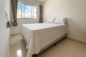 a white bed in a room with a window at Apto 2/4 com AR a 7min da Praia de Aruana in Santa Maria +35 photos