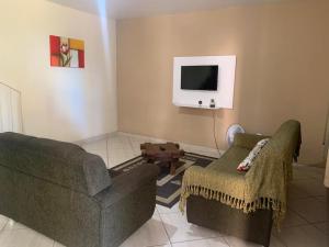 a living room with two couches and a tv at Penedo Reserva Apart Centro in Penedo