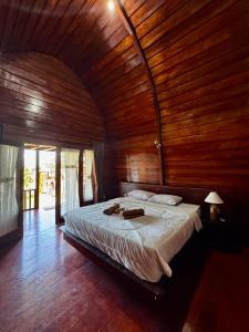 a bedroom with a large bed with a wooden ceiling at Koceng Bungalows in Tetebatu +26 photos