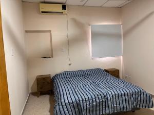 1 dormitorio con 1 cama con edredón de rayas azules en Buenos Aires Apart, en Charata