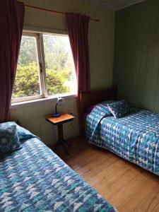 a bedroom with two beds and a window at Cómoda casa en Frutillar Bajo a 1 cuadra del Lago in Frutillar