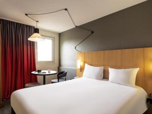 a hotel room with a large bed and a table at ibis Cergy Pontoise Le Port in Cergy