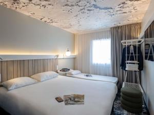 クレルモン・フェランにあるibis Clermont Ferrand Montferrandのベッドが2つあり、天井が見えるホテルの部屋