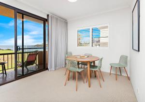 a dining room with a table and chairs and a balcony at Surfside 6 in Kiama +7 photos