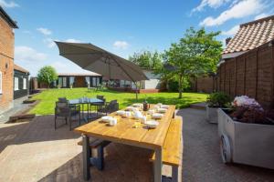 a patio with a wooden table and an umbrella at Old Cottage The Log Cabin in Bacton