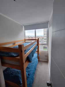 a bedroom with two bunk beds and a large window at Acogedor departamento sector Puertas del Mar in La Serena