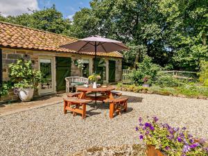 a patio with an umbrella and a table and benches at 1 Bed in Helmsley 93100 in Chop Gate