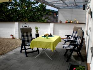 a table and two chairs with a yellow table cloth on a patio at Ferienwohnung Haus Gintz in Blieskastel