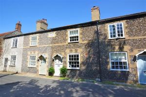 a large brick building with white doors and windows at Lavender Cottage in North Creake