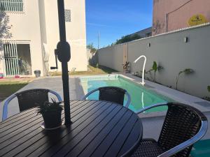 a black table and chairs and a swimming pool at Casa de Praia Castanheiras in Guriri