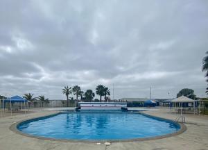 a large blue swimming pool with palm trees and umbrellas at Moderno Dpto vista al mar, piscina in Santa Elena