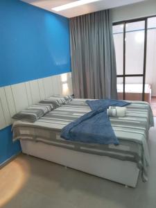 Cama grande en habitación con pared azul en Flat Season com Jacuzi, en Porto de Galinhas