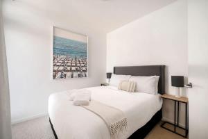 a bedroom with a large white bed with a picture on the wall at 212 - Amazing Apartment - Near Beach in Newcastle +15 photos