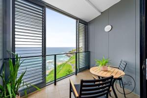 a balcony with a table and a view of the ocean at 803 - Stylish Retreat - Special Rates Through Dec 2025 in Newcastle