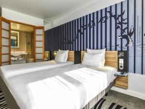 a bedroom with a large white bed in a room at Novotel La Rochelle Centre in La Rochelle