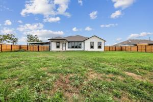a white house in a field with a fence at Modern Escape in Cedar Creek in Cedar Creek
