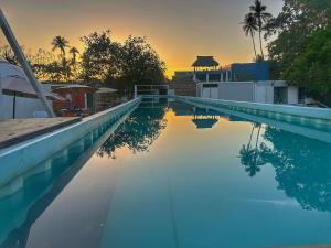 a swimming pool with a sunset in the background at Apple House cerca de la playa in Barra de Navidad