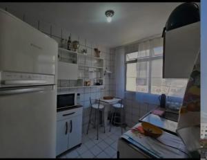 a kitchen with white appliances and a table in it at Apartamento Praia do Morro in Guarapari +2 photos