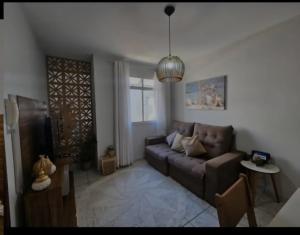a living room with a brown couch and a window at Apartamento Praia do Morro in Guarapari