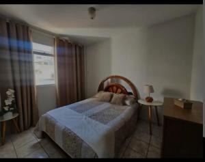 a bedroom with a bed and a window at Apartamento Praia do Morro in Guarapari