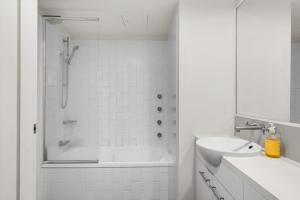 Un baño blanco con ducha y lavabo. en Open 1 Bedroom Apartment in Brisbane City, en Brisbane
