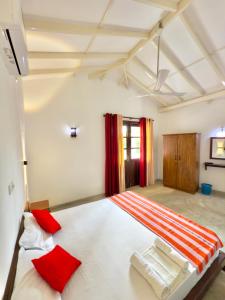 a bedroom with a large white bed with red pillows at Sayuru Villa in Hikkaduwa