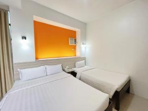 a hotel room with two beds and a window at Travelbee Business Inn in Cebu City +28 photos