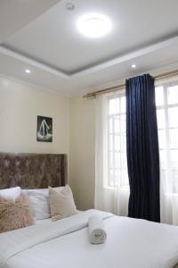 a bedroom with a large white bed with a blue curtain at Bliss Park B & B in Athi River
