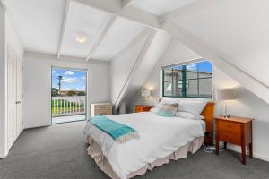 Waipu CoveにあるCove Family Haven - Waipu Holiday Homeのベッドと窓のある白い寝室