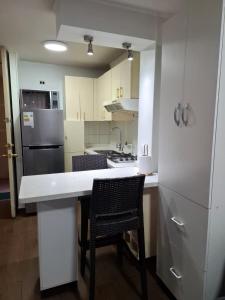 a kitchen with white cabinets and a counter with chairs at Santiago Skyline Suites in Santiago