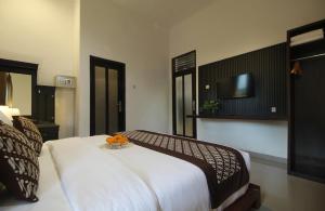 a bedroom with a bed and a tv on the wall at Dhanya Villa Lovina by Parigata in Singaraja +21 photos