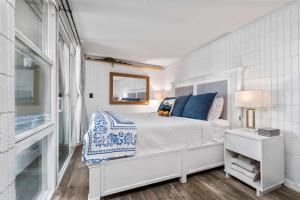 a white bedroom with a bed and a mirror at Beachfront Studio with Partial Ocean View in Punaluu