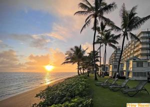 a beach with chairs and palm trees at sunset at Beachfront Studio with Partial Ocean View in Punaluu
