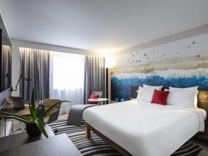 a hotel room with a large white bed and a couch at Novotel Bordeaux Centre Ville in Bordeaux
