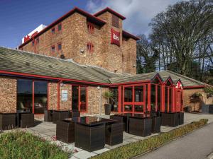 un gran edificio de ladrillo con mesas delante en Ibis London Luton Airport, en Luton