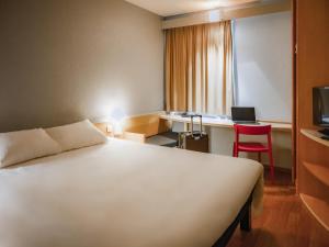 a hotel room with a white bed and a desk at ibis Colmar Est - Hotel Restaurant en Alsace in Colmar