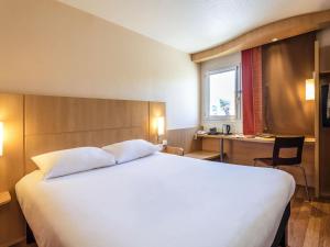 a bedroom with a large white bed and a desk at Ibis Château-Thierry in Essômes-sur-Marne