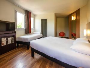 a hotel room with two beds and a tv at Ibis Château-Thierry in Essômes-sur-Marne +131 photos