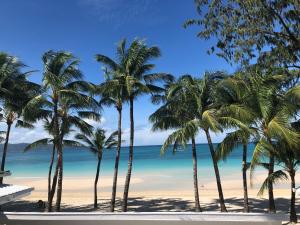 a group of palm trees on a beach with the ocean at Kyle's Bed and Breakfast DMall Boracay in Boracay
