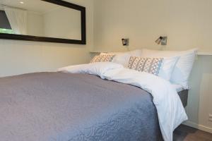 a bedroom with a bed with a mirror on the wall at Krøgeneslåven Microtel in Arendal